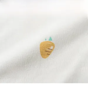 Vue détaillée du bavoir en coton blanc pour bébé avec motifs carottes orange vifs
