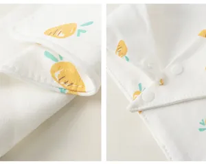 Détail du bavoir en coton pour bébé avec imprimés carottes, bouton pression et coutures