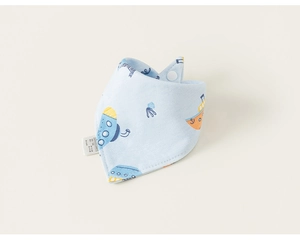 Gros plan d'un bavoir bleu clair pour bébé avec bateaux et bouton pression blanc