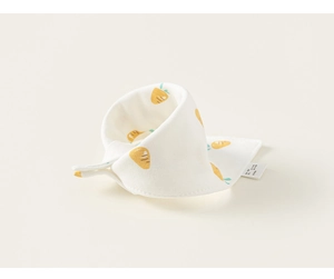 Détail du bavoir en coton pour bébé avec motifs carottes et étiquette de lavage