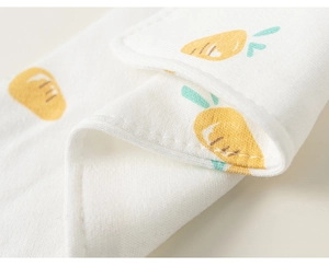 Détail d'un bavoir en coton pour bébé avec imprimé carotte et bordure à double couture