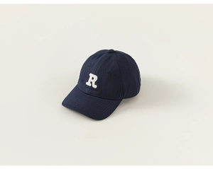 Detail of navy blue kids baseball cap showing white letter R embroidery and fabric texture