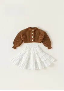 Detailed close-up of girls brown knit cardigan with metal buttons and white lace skirt