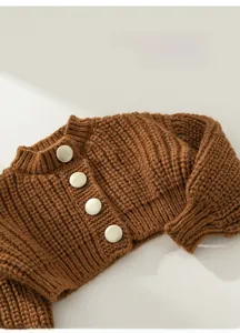 Detailed close-up of brown chunky knit cardigan featuring large cream-colored buttons