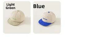 Detail view of baby sun hats in light green and blue with Good Day embroidery