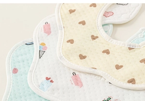 Détail de bavoirs en coton en forme de fleur avec motifs mignons et bouton pression