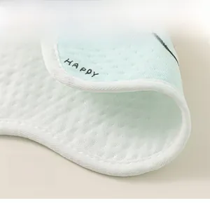 Vue macro d'un bavoir en coton respirant avec bordure bleue et détail de lettrage