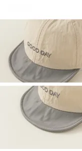 Detail of baby sun hat with GOOD DAY embroidery and beige grey contrast nylon fabric