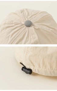 Detail view of the beige baby sun hat showing the stitching and black adjustable cord