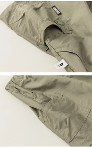 Gedetailleerde macro-opname van olijfgroene cargoshorts met elastische taille en geweven merklabel