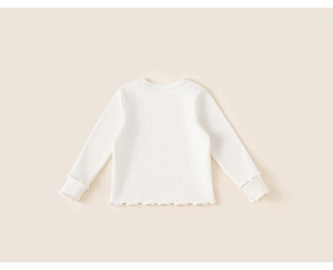 Dettaglio maglia bianca a maniche lunghe da bambina con eleganti bordi a volant rifiniti