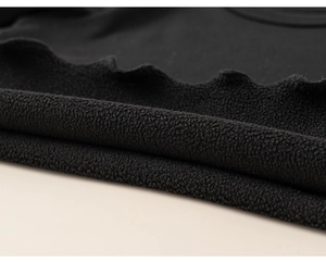 Dettaglio del tessuto in pile nero con bordo a onde su una maglia a maniche lunghe bimba