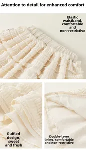Detail of elastic waistband and layered lace ruffles on cream girls' skirt