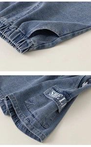 Detail of boys denim shorts showing elastic waistband and side cargo pocket with text