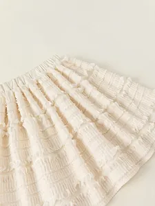 Creamy white layered ruffle skirt for girls featuring pleated fabric and elastic waist
