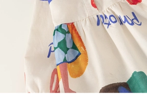 Detailed view of kids cotton dress with colorful parrot doodle print and pleated texture