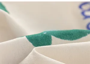 Close-up of cotton fabric texture with green floral patterns and blue typography