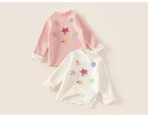 Close-up of pink and beige kids tops with ruffle edges and star heart patches