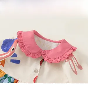 Detailed view of kids' sleeveless dress with pink ruffle collar and cartoon prints