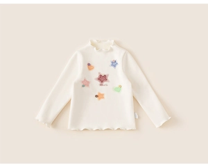 Close-up of cream knit top featuring ruffled edges and colorful star heart patches