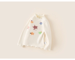 Detail of baby girl cream t-shirt with colorful stars and ruffled lettuce edge hem