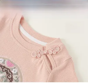 Detail of pink Chinese style knitted top showing ribbed texture, frog button, and floral embroidery