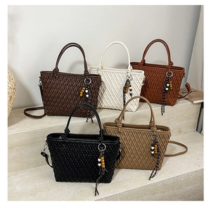 Detail view of five woven bucket bags with wood bead charms on stone steps