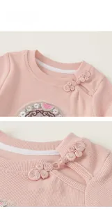 Detail of pink knitted baby top featuring traditional Chinese frog buttons and embroidery