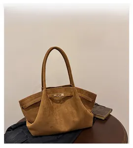 Detail of brown suede tote bag featuring a golden metal buckle lock and side straps
