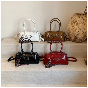 Présentation de quatre sacs Boston en cuir brillant vintage avec des breloques tressées