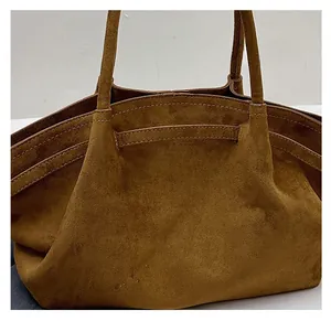Close-up detail of soft brown suede tote bag with decorative stitching and twin handles