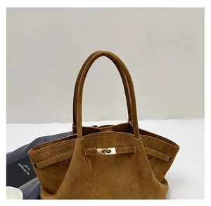 Detail of the brown suede tote bag featuring a golden twist lock and soft handles