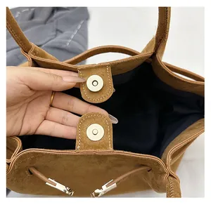 Detail of magnetic snap closure on a minimalist dark brown suede tote shoulder bag