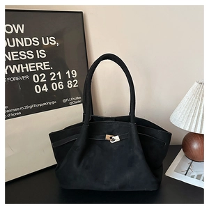 Close-up of black suede tote bag featuring a metallic twist-lock closure and modern design