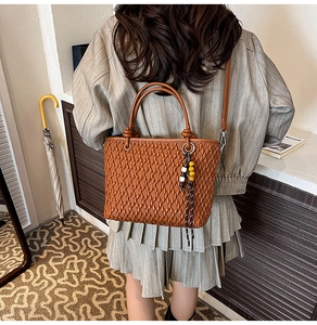 Brown woven bucket bag with elegant wooden beads and long shoulder strap in lifestyle setting