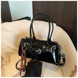 Détail du sac à main en cuir verni noir avec finition miroir et décoration tressée