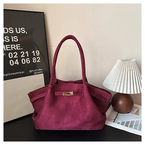 Detail of burgundy suede tote bag showing the golden twist lock and soft texture