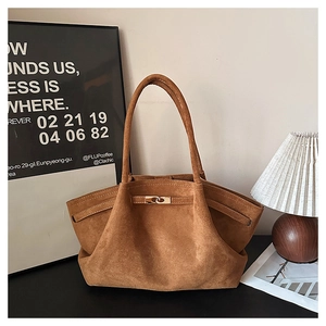 Detail of caramel suede tote bag featuring a golden twist lock and a winged silhouette