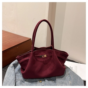 Detail of burgundy suede tote bag featuring metallic buckle on textured blue denim