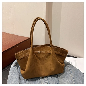 Detail of soft brown suede tote bag featuring a decorative strap and metal buckle accent