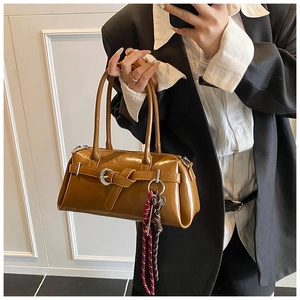Détail d'un sac à bandoulière en cuir verni marron avec un accessoire en foulard de soie