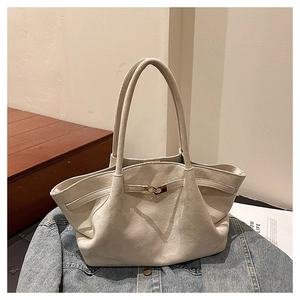 Close-up of cream suede tote bag with golden metal buckle on denim jacket background