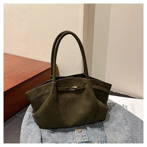 Detail view of olive green suede tote bag with decorative silver buckle on denim fabric