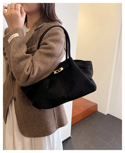 Detail of black suede tote bag with golden metal turn-lock and spacious design
