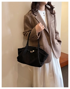 Detail of minimalist black suede tote bag showing the golden metal twist lock closure