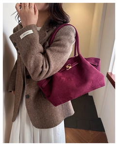 Detailed macro view of burgundy suede tote bag with gold lock and drawstring texture