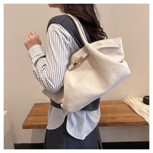 Close-up of minimalist beige suede tote bag with elegant gold metal buckle detail