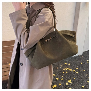 Close-up of dark green suede tote bag with silver metal twist lock and strap details