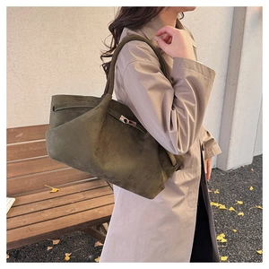 Detail of moss green suede tote bag with silver buckle in an autumn street setting