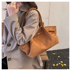Close-up of brown suede tote bag with silver twist lock on an autumn park bench